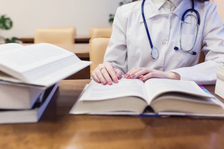 Understanding the Reasons for Medical School Dismissal: What Students Should Know background a medical student for textbooks. The study of surgery by a beautiful girl in the library